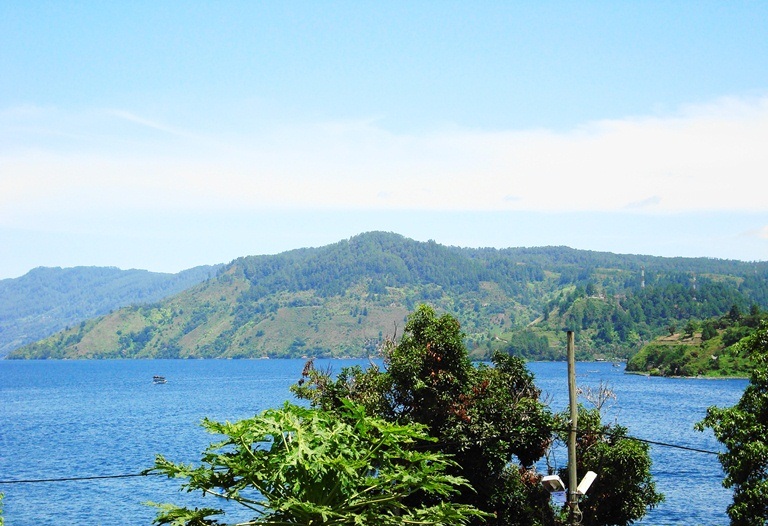 Pemandangan Danau Toba dan perbukitan pada siang hari